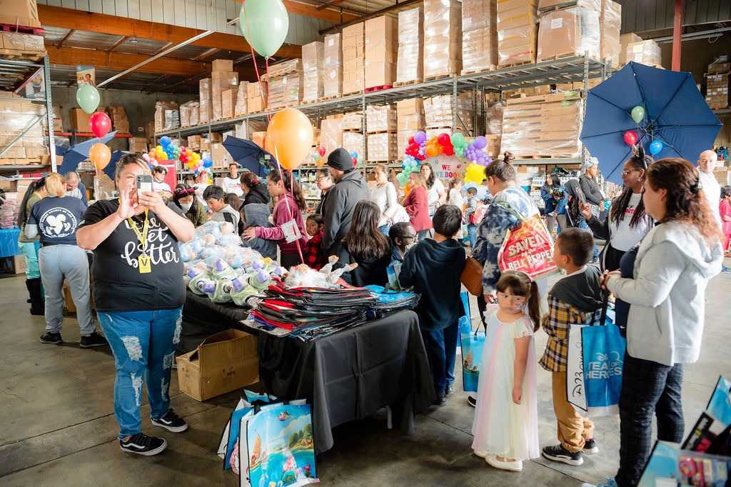 A lively community event in a warehouse, where families gather around tables filled with gifts and balloons, celebrating together.